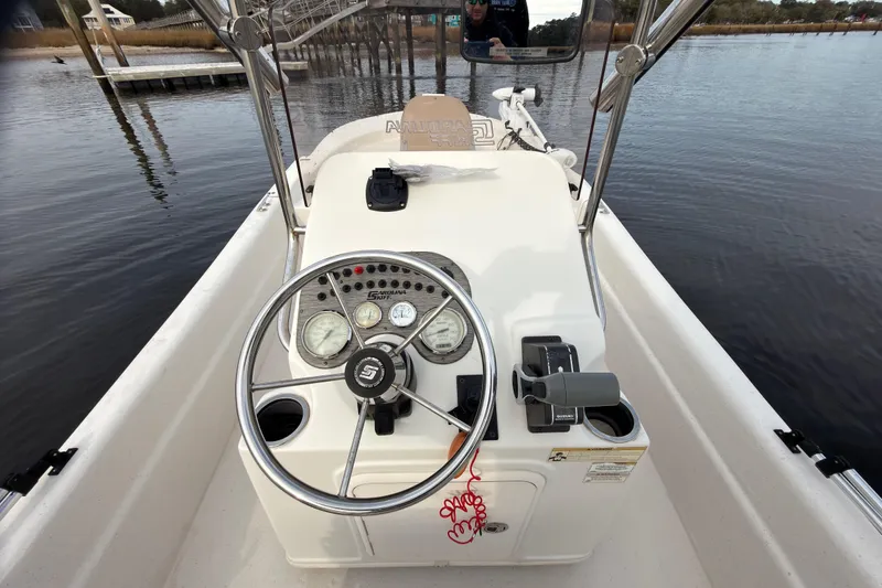 Slide: The Image of 2017 Carolina Skiff 18 JVX CC boat console with steering wheel and gauges on calm water. - 6