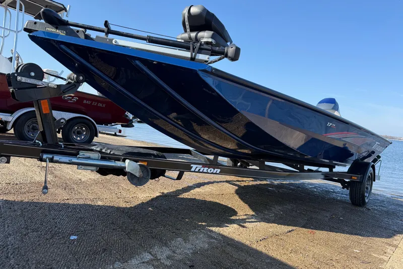 Slide: The Image of 2020 Triton 17 TX boat on trailer by the water, featuring sleek blue design. - 15