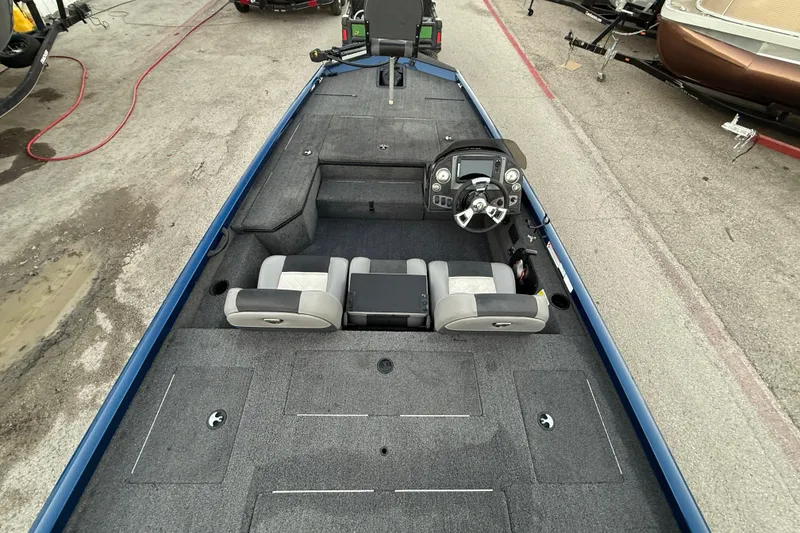 Slide: The Image of 2020 Triton 17 TX boat interior with steering console and seating, parked on pavement. - 55
