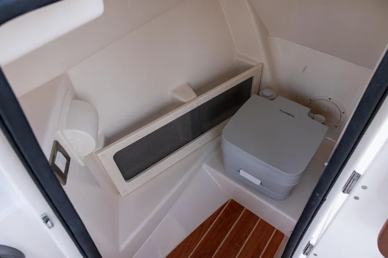 Slide: The Image of 2021 Grady-White Freedom 215 boat interior with portable toilet and wooden flooring. - 11