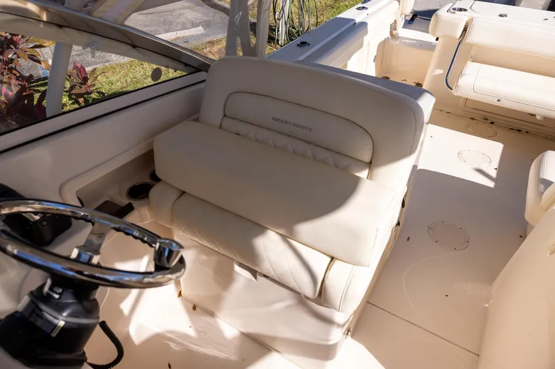 Slide: The Image of 2022 Grady-White Freedom 275 boat interior with steering wheel and cushioned seating. - 13