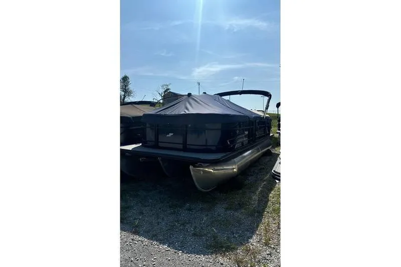The Image of 2024 Starcraft EXS 3 Q pontoon boat with cover, parked outdoors under sunny sky. - 0