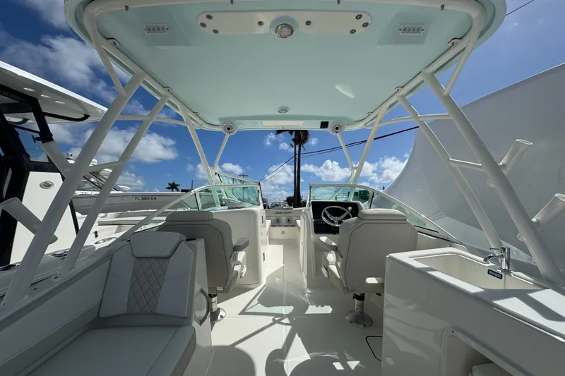 Slide: The Image of 2026 World Cat 230 SD boat interior with seating, steering wheel, and sink under a clear sky. - 14