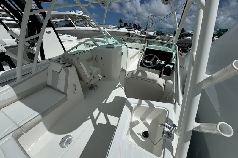 Slide: The Image of 2026 World Cat 230 SD boat interior with helm, seating, and sink under a blue sky. - 9