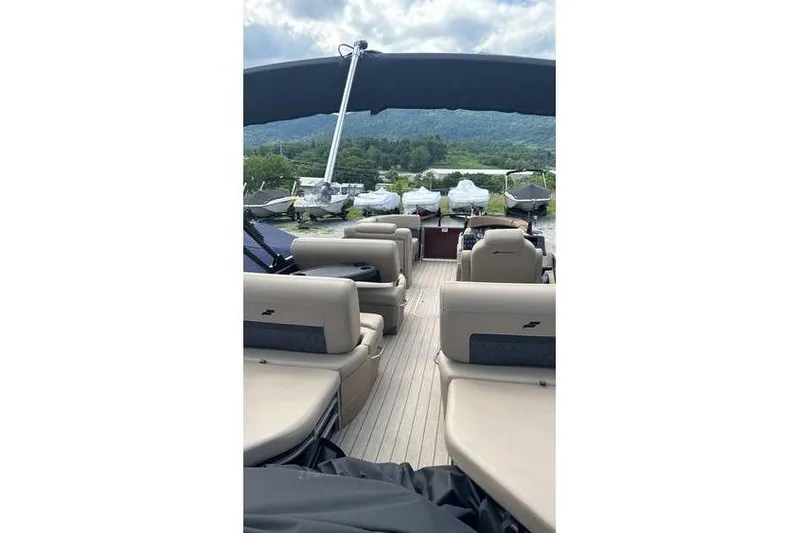 Slide: The Image of 2024 Starcraft CX 23 RL pontoon boat with spacious seating and scenic mountain backdrop. - 2
