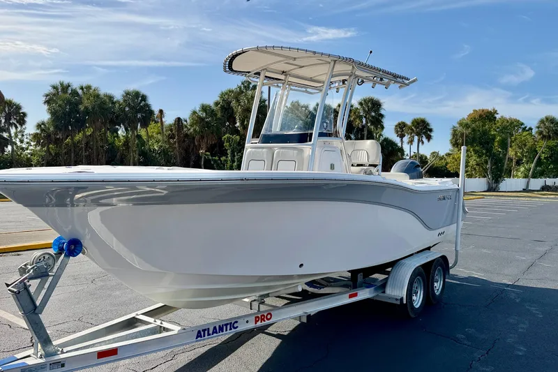 Slide: The Image of 2023 Sea Fox 228 Commander boat on trailer, parked with palm trees in background. - 2
