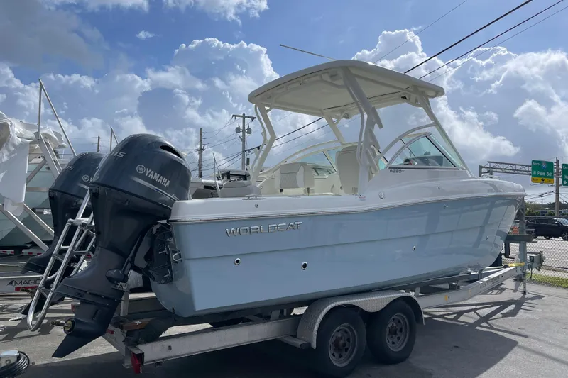 Slide: The Image of 2025 World Cat 230 DC boat on trailer with Yamaha engines, under a cloudy sky. - 2