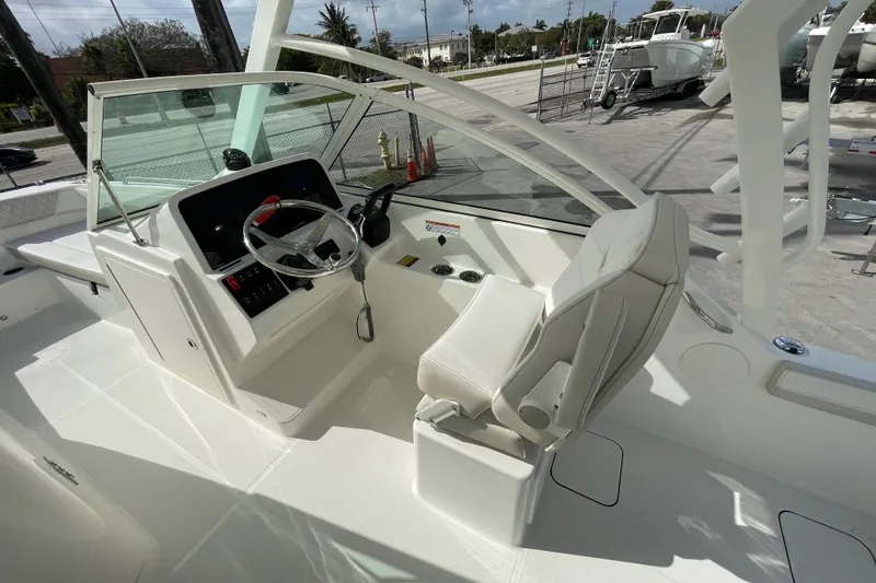 Slide: The Image of 2025 World Cat 230 DC boat cockpit with steering wheel and captain's chair. - 8