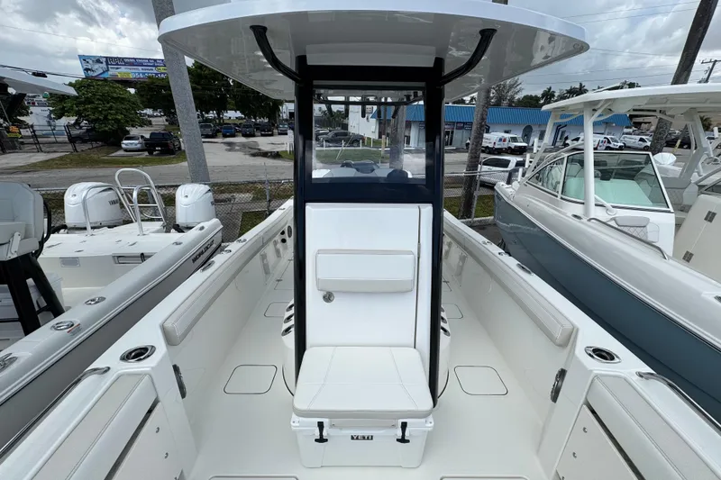 Slide: The Image of 2026 World Cat 235 TE boat interior with seating and console, displayed at a marina. - 12