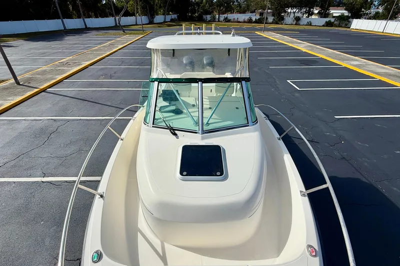 Slide: The Image of 1999 Pursuit 2470 Walkaround boat parked in an empty lot, top view. - 11