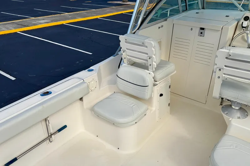 Slide: The Image of 1999 Pursuit 2470 Walkaround boat interior with white seating and storage compartments. - 13