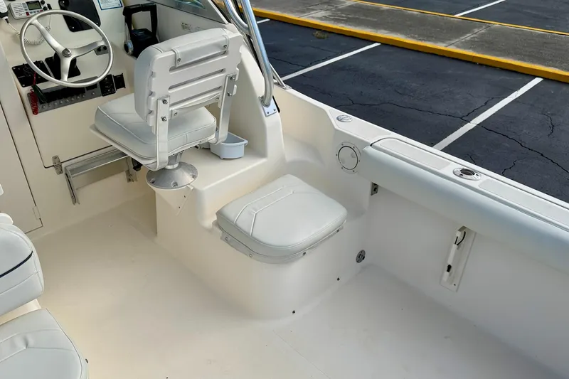 Slide: The Image of 1999 Pursuit 2470 Walkaround boat interior with white seating and steering wheel. - 14