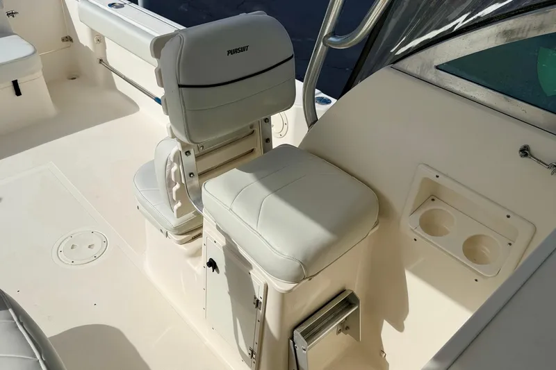 Slide: The Image of 1999 Pursuit 2470 Walkaround boat interior with white seating and cup holders. - 16
