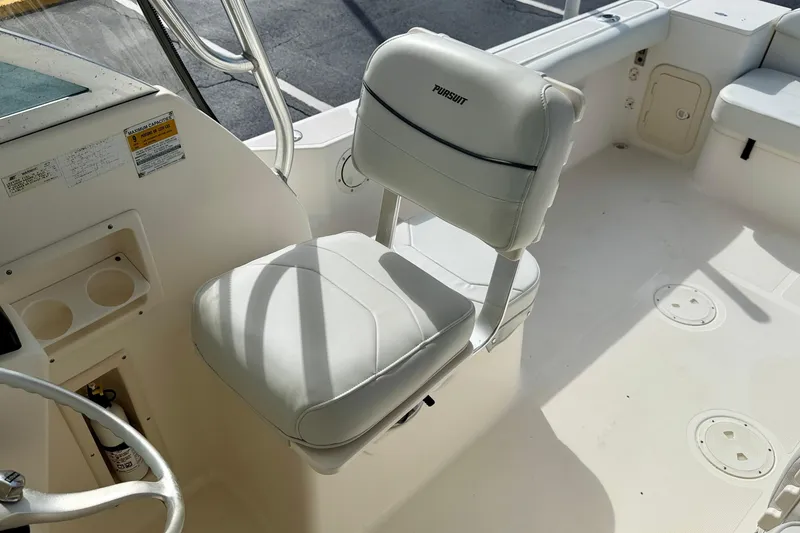 Slide: The Image of 1999 Pursuit 2470 Walkaround boat interior with white captain's chair and steering wheel. - 17
