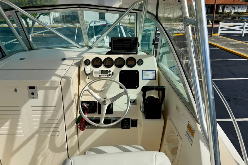 Slide: The Image of 1999 Pursuit 2470 Walkaround boat cockpit with steering wheel and control panel. - 18