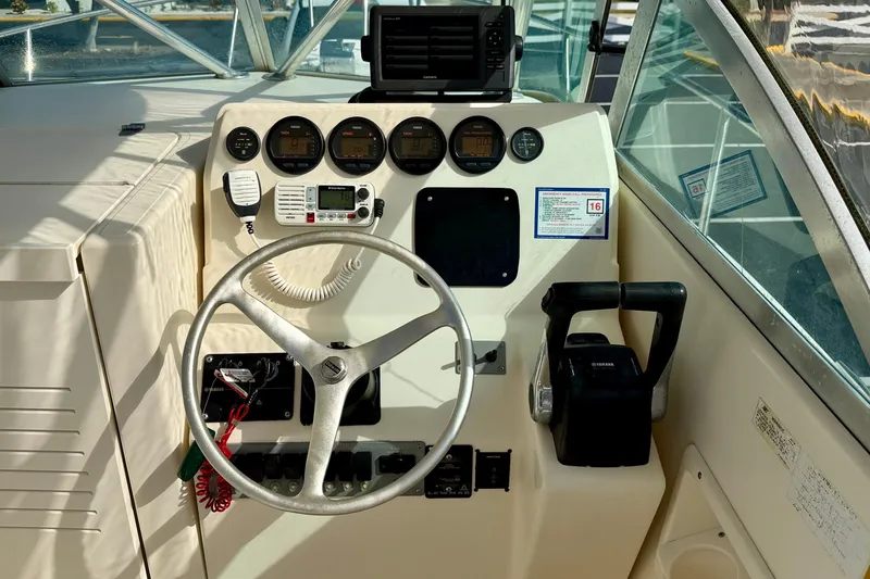Slide: The Image of 1999 Pursuit 2470 Walkaround boat dashboard with steering wheel and control panel. - 19