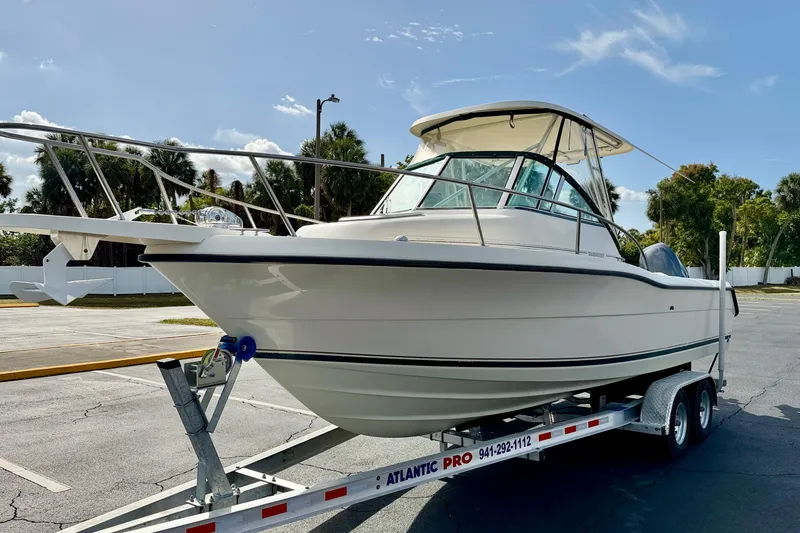 Slide: The Image of 1999 Pursuit 2470 Walkaround boat on trailer in sunny parking lot. - 2