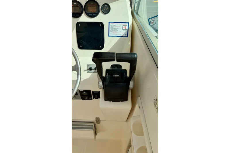 Slide: The Image of 1999 Pursuit 2470 Walkaround boat dashboard with steering wheel and controls. - 20