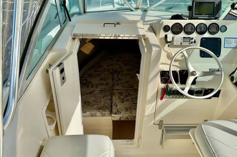 Slide: The Image of 1999 Pursuit 2470 Walkaround boat interior with steering wheel and cabin entrance. - 25