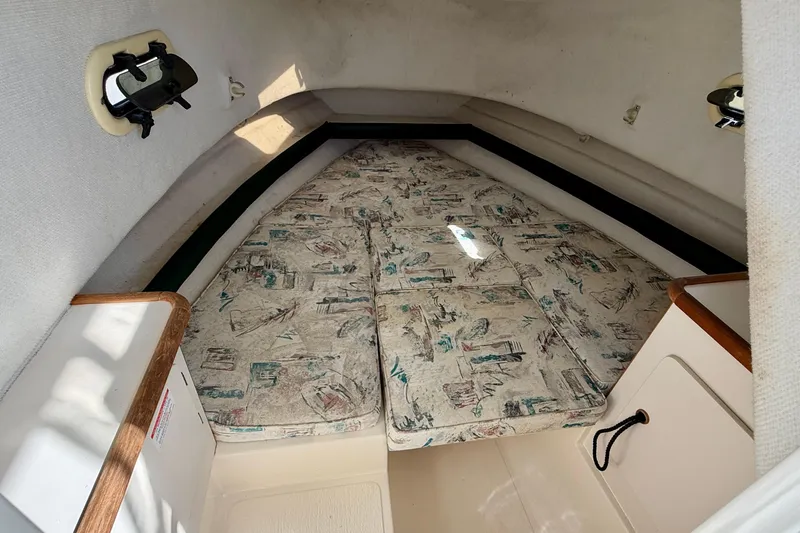 Slide: The Image of 1999 Pursuit 2470 Walkaround cabin interior with patterned cushions and compact design. - 26