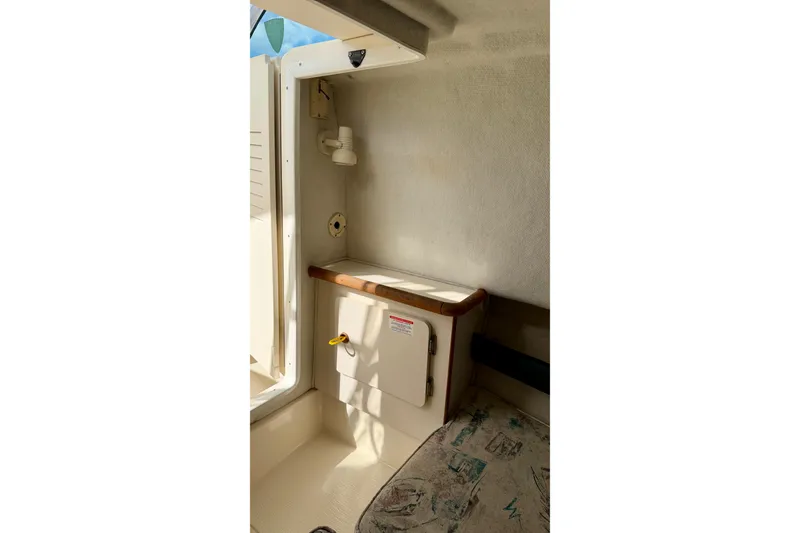 Slide: The Image of Interior cabin of a 1999 Pursuit 2470 Walkaround boat, featuring storage and seating. - 28