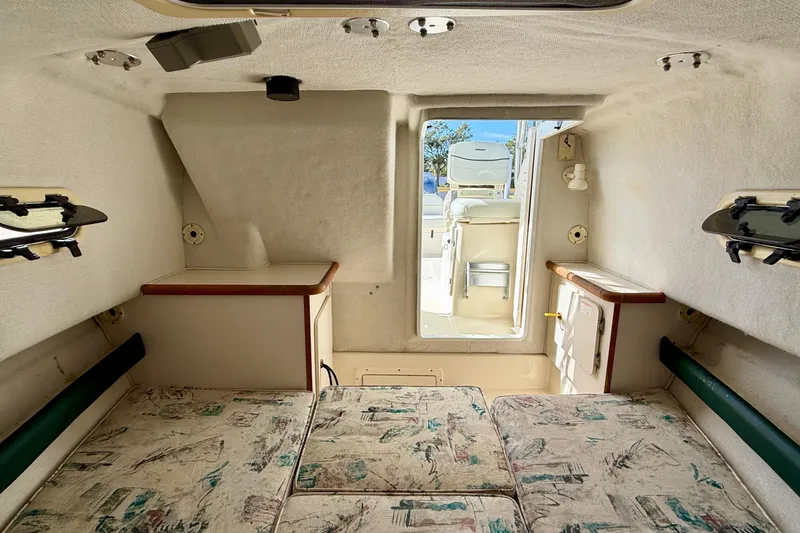 Slide: The Image of Interior cabin of a 1999 Pursuit 2470 Walkaround boat, featuring seating and storage. - 29