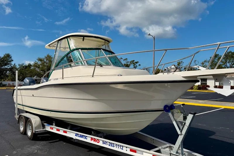 Slide: The Image of 1999 Pursuit 2470 Walkaround boat on trailer under blue sky. - 4