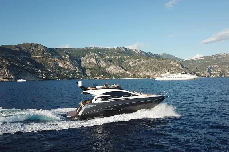 Slide: The Image of 2025 Cobrey 52 FLY yacht cruising on scenic coastal waters with mountains in the background. - 2