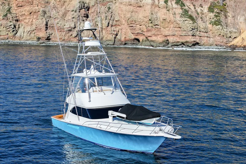 Slide: The Image of 2013 Viking 46 Convertible yacht on calm waters near rocky coastline. - 5