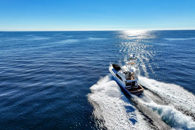 Slide: The Image of 2013 Viking 46 Convertible yacht cruising on open ocean under clear blue sky. - 68