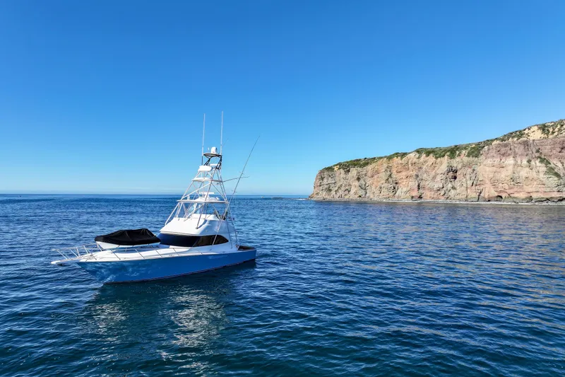 Slide: The Image of 2013 Viking 46 Convertible yacht on calm ocean near rocky coastline under clear blue sky. - 75