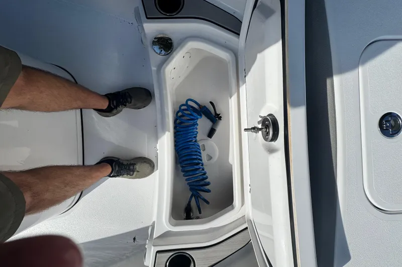 Slide: The Image of 2024 Sportsman Masters 247OE Bay Boat deck with storage compartment and coiled hose. - 17
