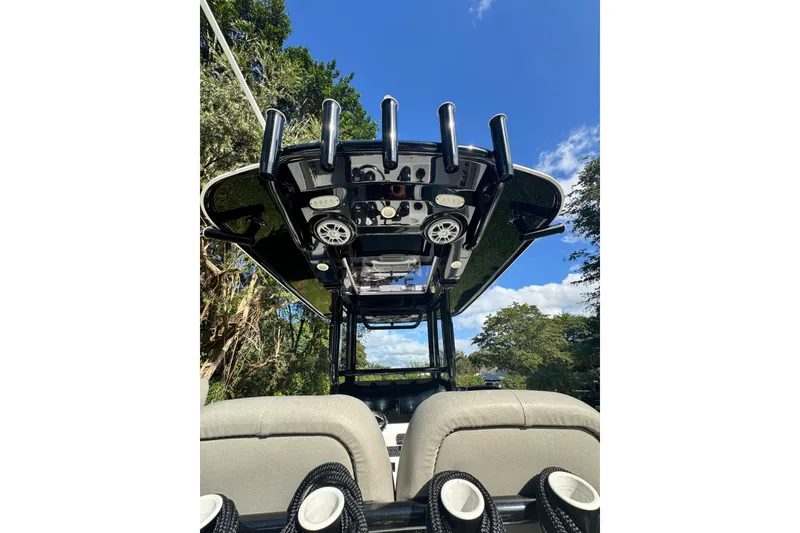 Slide: The Image of 2024 Sportsman Masters 247OE Bay Boat, view of T-top and seating, under clear blue sky. - 19