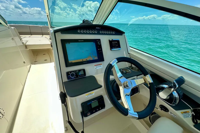 Slide: The Image of 2018 Boston Whaler 320 Vantage helm with navigation display, steering wheel, and ocean view. - 14