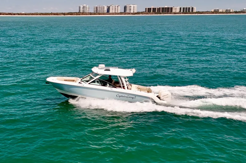 Slide: The Image of 2018 Boston Whaler 320 Vantage cruising on open water with city skyline in background. - 32