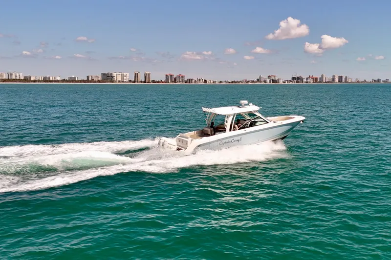 Slide: The Image of 2018 Boston Whaler 320 Vantage cruising on turquoise waters near a city skyline. - 37