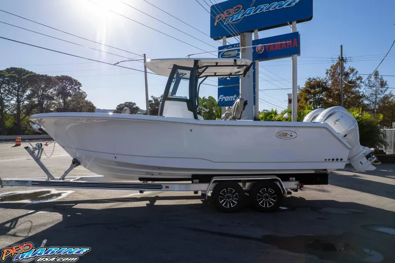 Slide: The Image of 2026 Sea Hunt Gamefish 25 boat on trailer at dealership under clear sky. - 4