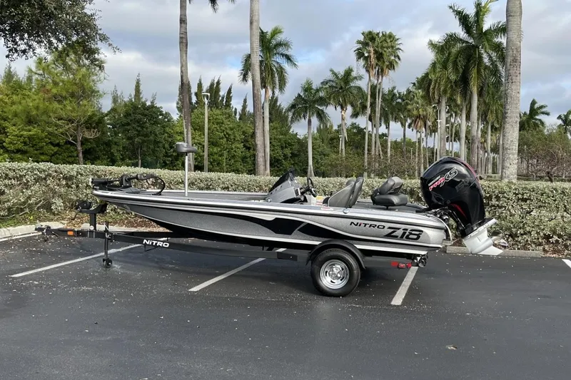 Slide: The Image of 2024 Nitro Z18 boat parked, featuring sleek design and powerful engine, surrounded by palm trees. - 0