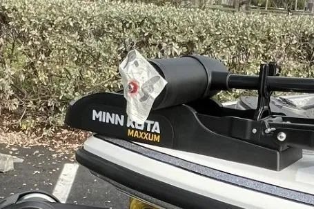 Slide: The Image of Minn Kota Maxxum motor on 2024 Nitro Z18 boat, parked near hedges. - 13