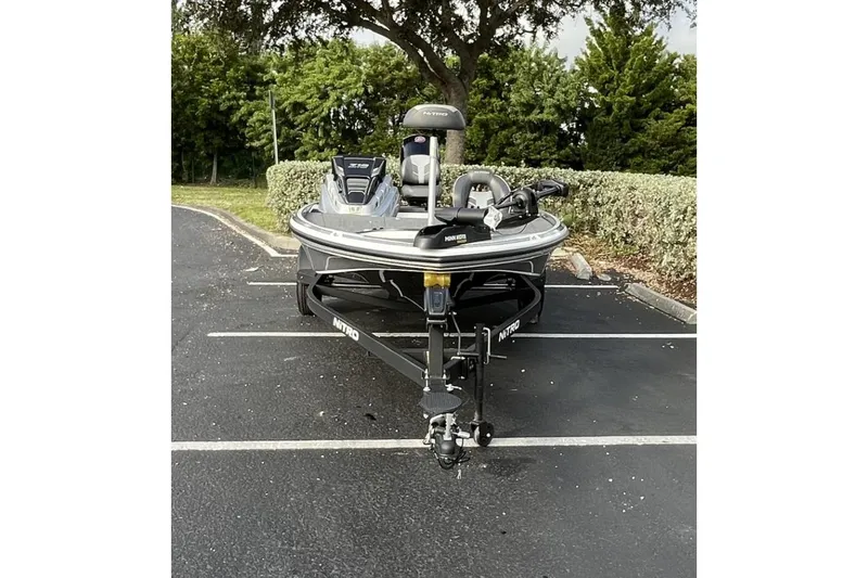 Slide: The Image of 2024 Nitro Z18 boat parked in a lot, surrounded by greenery. - 2