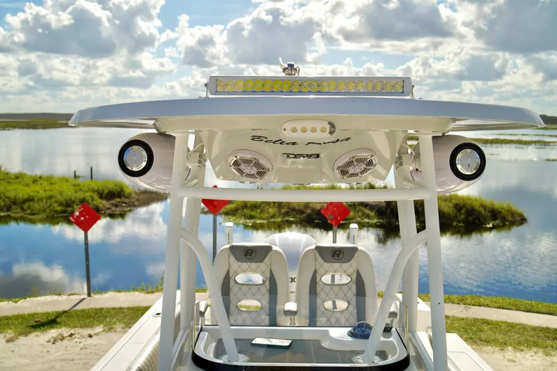 Slide: The Image of 2017 Release 240 RX boat with T-top, speakers, and scenic water backdrop. - 12