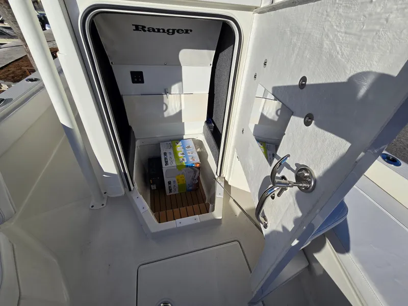 Slide: The Image of 2025 Ranger 2360 Bay boat storage compartment with wooden flooring and a beverage pack inside. - 10