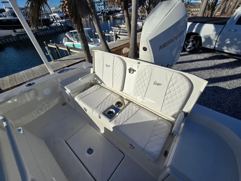 Slide: The Image of 2025 Ranger 2360 Bay boat interior with cushioned seating and cup holders at a marina. - 14