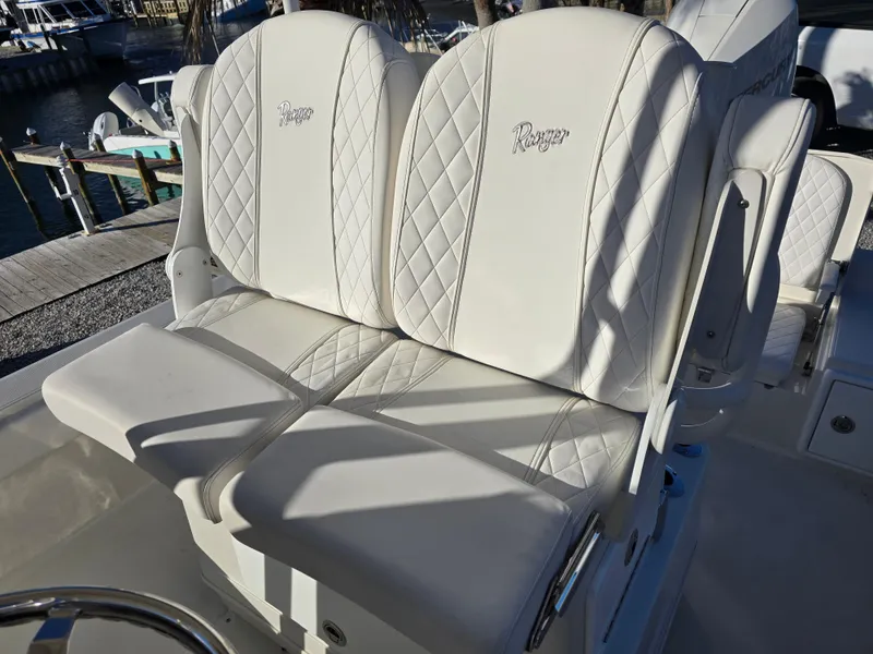 Slide: The Image of 2025 Ranger 2360 Bay boat with luxurious white leather seats, dockside view. - 18