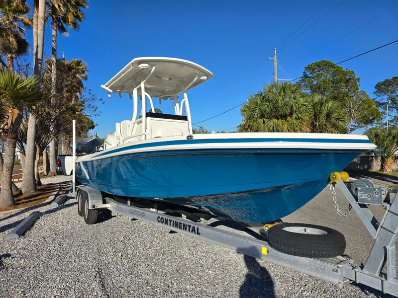 Slide: The Image of 2025 Ranger 2360 Bay boat on trailer, parked outdoors under clear blue sky. - 3