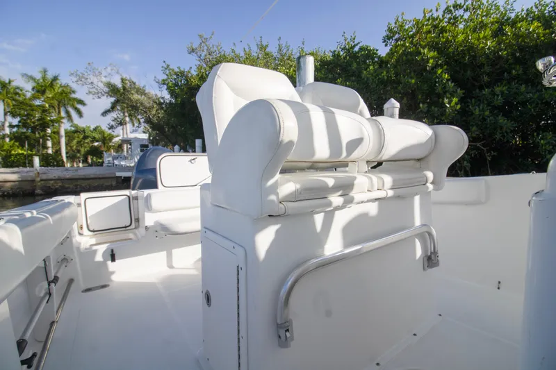 Slide: The Image of 2014 Sea Hunt Gamefish 25 boat interior with white seating and lush greenery backdrop. - 11