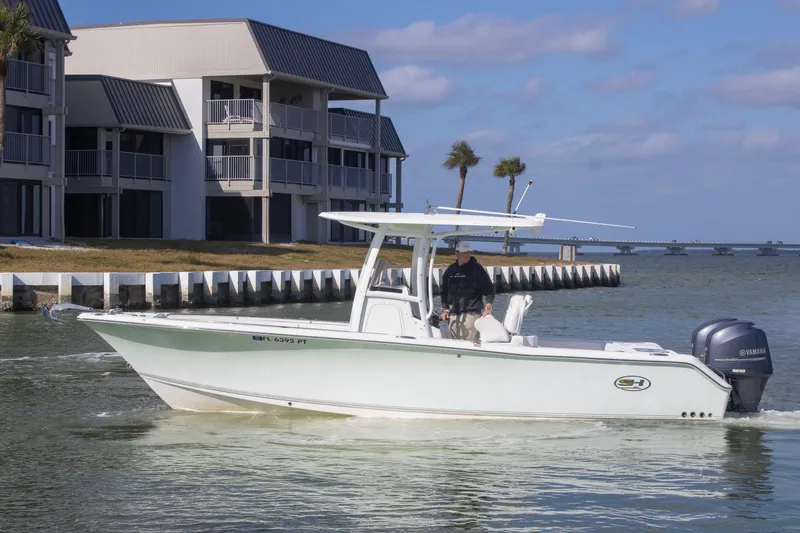 Slide: The Image of 2014 Sea Hunt Gamefish 25 boat cruising near waterfront buildings. - 2