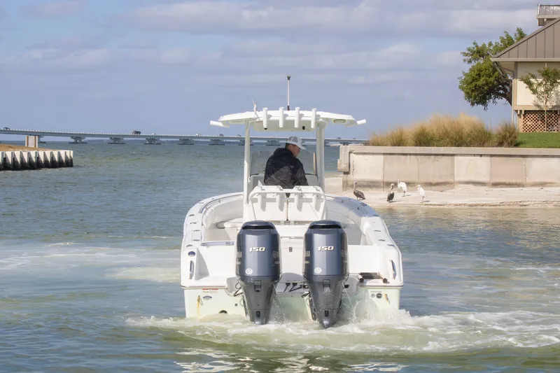 Slide: The Image of 2014 Sea Hunt Gamefish 25 boat navigating coastal waters near a bridge. - 3