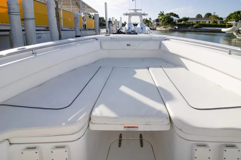 Slide: The Image of 2014 Sea Hunt Gamefish 25 boat interior with cushioned seating, docked by the water. - 4