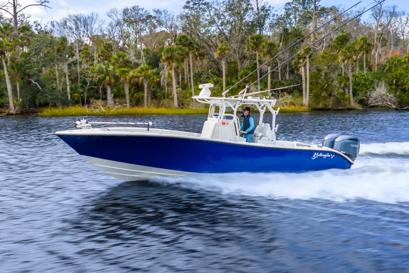 Slide: The Image of 2014 Yellowfin 32 Offshore boat cruising on a scenic river with lush forest backdrop. - 11